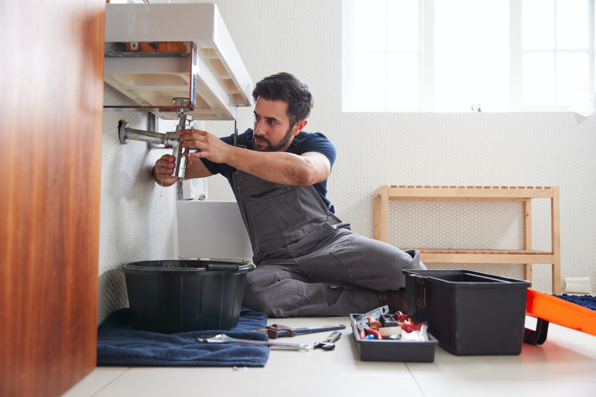 male-plumber-working-to-fix-leaking-sink-in-home-bathroom.jpg